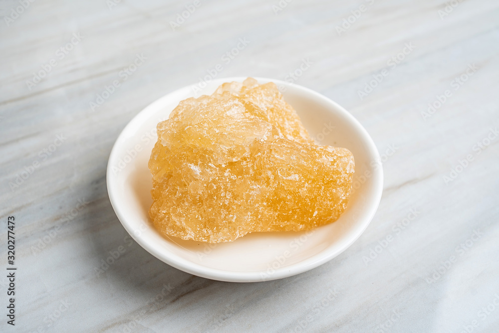 A dish of yellow rock sugar on the kitchen tile countertop A dish of yellow rock sugar on the kitchen tile countertop
