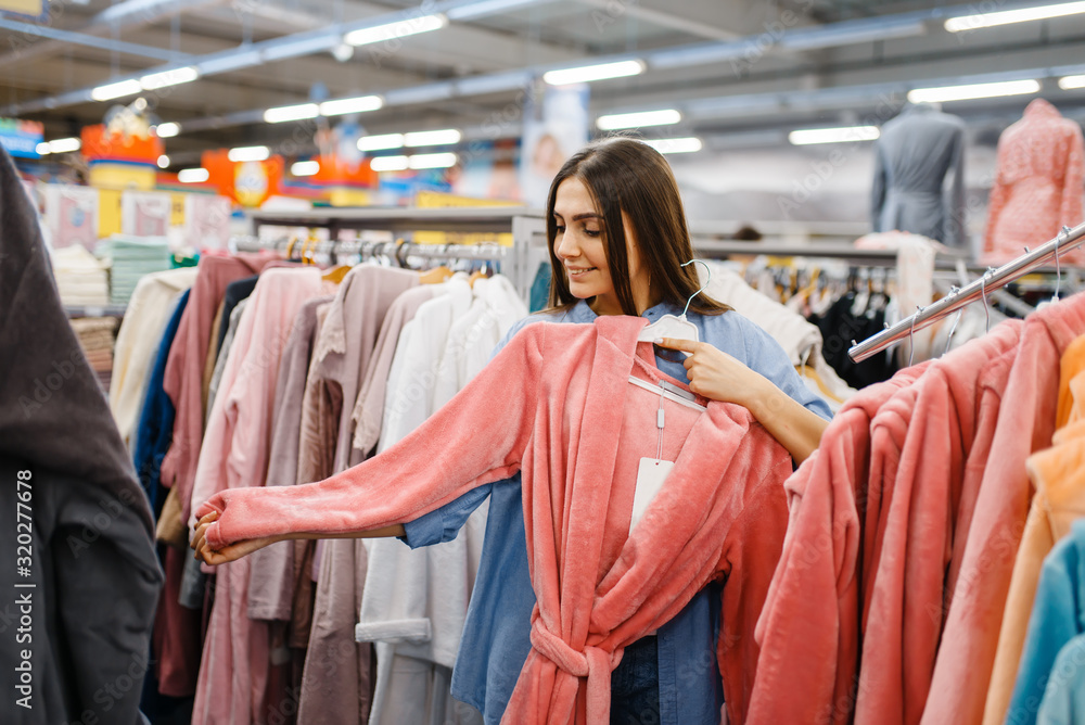 Young woman choosing bathrobe in bed linen store Young woman choosing bathrobe in bed linen store