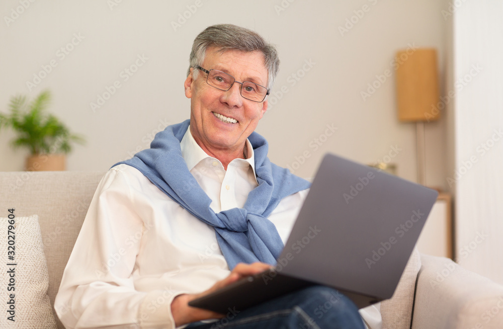 Cheerful Elderly Man With Laptop Computer Sitting On Sofa Indoor Cheerful Elderly Man With Laptop Computer Sitting On Sofa Indoor
