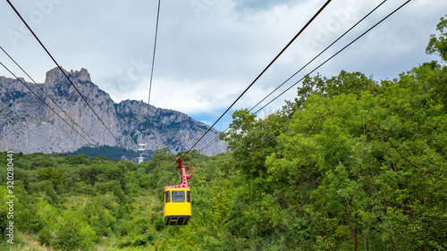 Beautiful aerial view of the mountains whose slopes are covered with green forest from the yellow cab of the funicular rising to the top of the mountain. Cable car in the Crimean mountains, Ai-Petri.