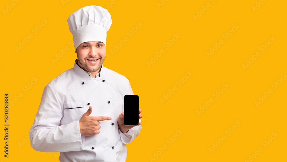 Positive Chef Holding Phone With Blank Screen Over Yellow Background Positive Chef Holding Phone With Blank Screen Over Yellow Background