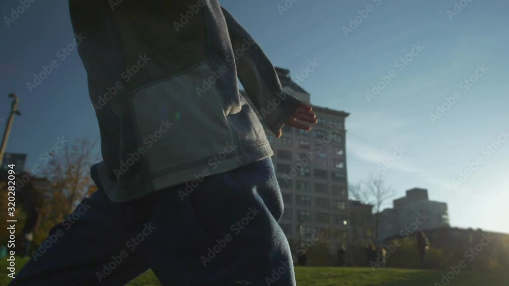 Boy smiling laughing and running in a park under the Manhattan Bridge, in 120fps slow motion, with sun on his face. Brooklyn Bridge and lower Manhattan in the distance. Boy smiling laughing and running in a park under the Manhattan Bridge, in 120fps slow motion, with sun on his face. Brooklyn Bridge and lower Manhattan in the distance.