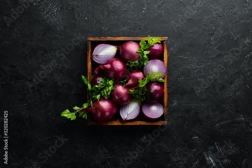 Purple onion in wooden box on black background. Top view. Free copy space.
