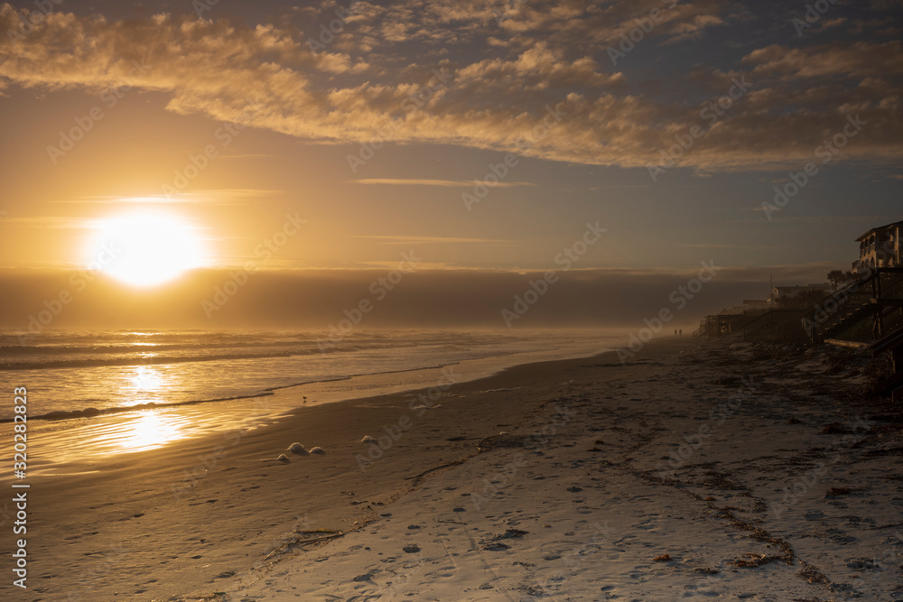 A silhouetted couple walks down the beach in Port Orange, Florida during a sunrise.