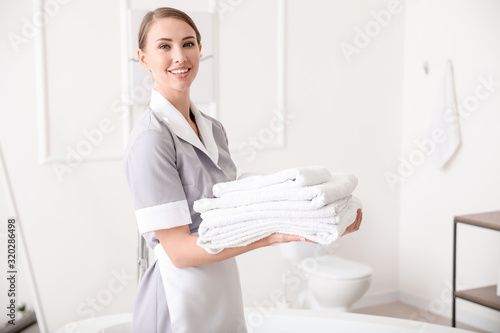 Obraz na plátně Beautiful chambermaid with clean towels in hotel bathroom