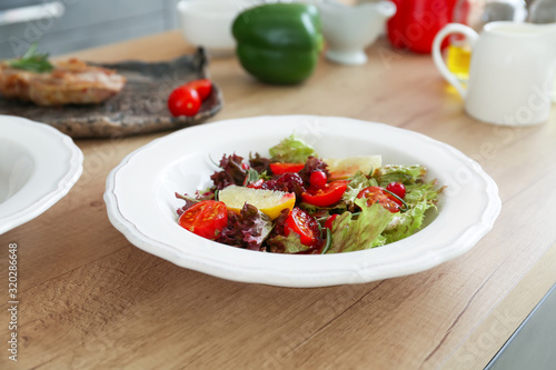 Plate with tasty prepared salad on table in kitchen