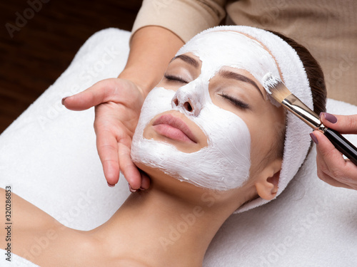 Woman receiving facial mask at beauty salon