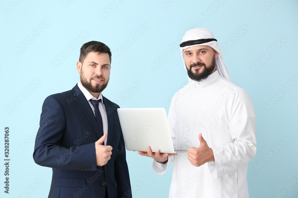 Arab man and his business partner with laptop on color background Arab man and his business partner with laptop on color background