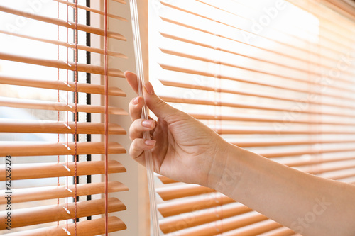 Woman opening blinds on window photo