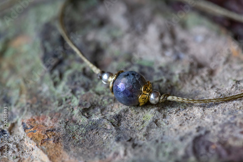 Labradorite fazeted gemstone tiny bracelet on rocky background photo