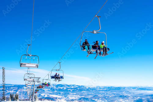 Skiers on chairlift at mountain ski resort with beautiful winter landscape in the background