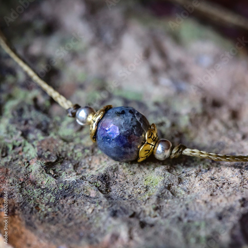 Labradorite fazeted gemstone tiny bracelet on rocky background photo