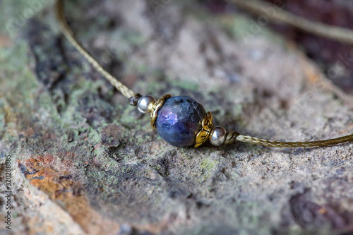 Labradorite fazeted gemstone tiny bracelet on rocky background photo