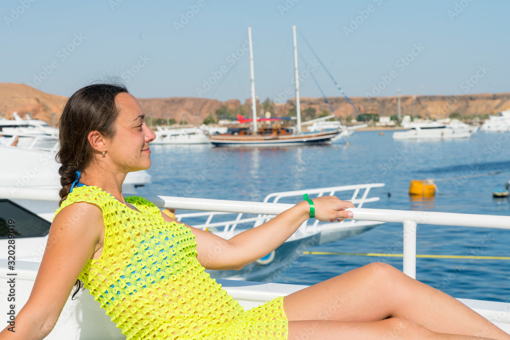 Happy middle aged woman relaxing on a yacht at sea. Woman relaxing on board of sailing yacht