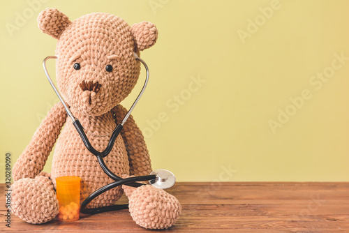Stethoscope, pills and baby toy on table photo