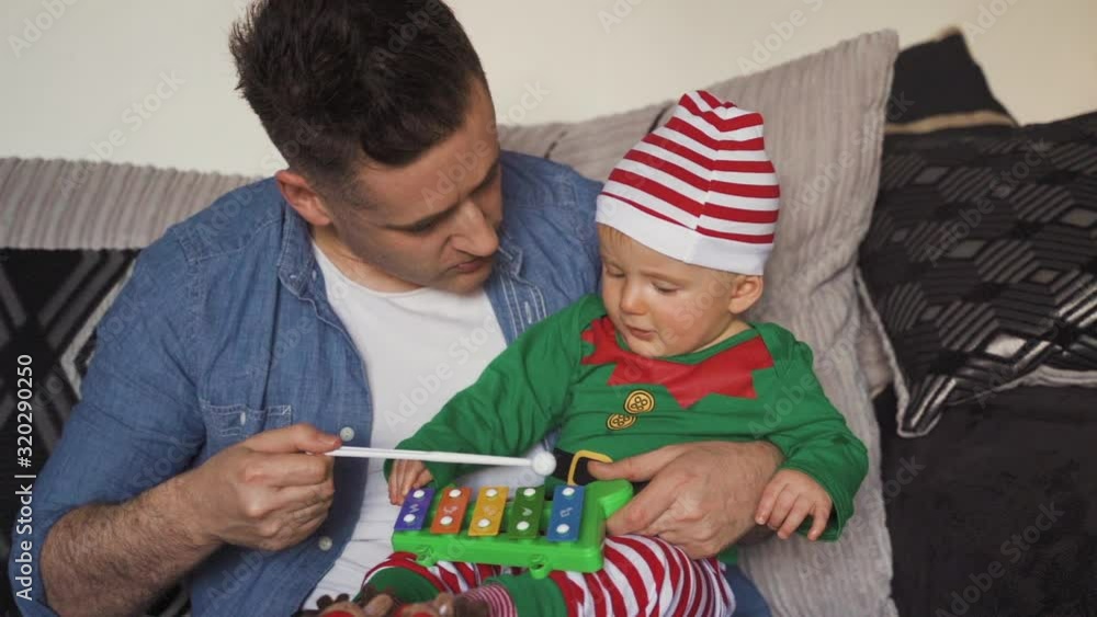 Dad and baby elf son playing xylophone on Christmas morning. Little boy