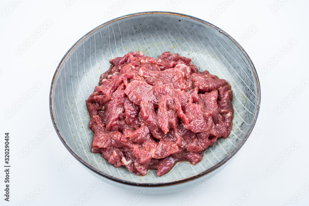 Fresh marinated beef slices on a plate on white background Fresh marinated beef slices on a plate on white background