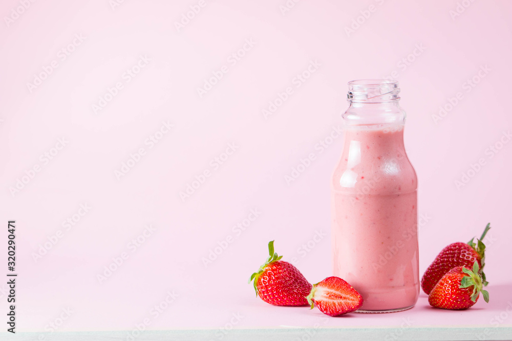 Glass of fresh strawberry milkshake, smoothie and fresh strawberries on pink, white and wooden background. Healthy food and drink concept. Glass of fresh strawberry milkshake, smoothie and fresh strawberries on pink, white and wooden background. Healthy food and drink concept.