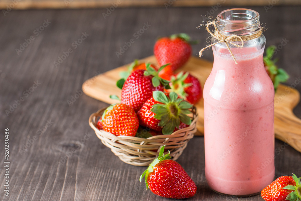 Glass of fresh strawberry milkshake, smoothie and fresh strawberries on pink, white and wooden background. Healthy food and drink concept. Glass of fresh strawberry milkshake, smoothie and fresh strawberries on pink, white and wooden background. Healthy food and drink concept.
