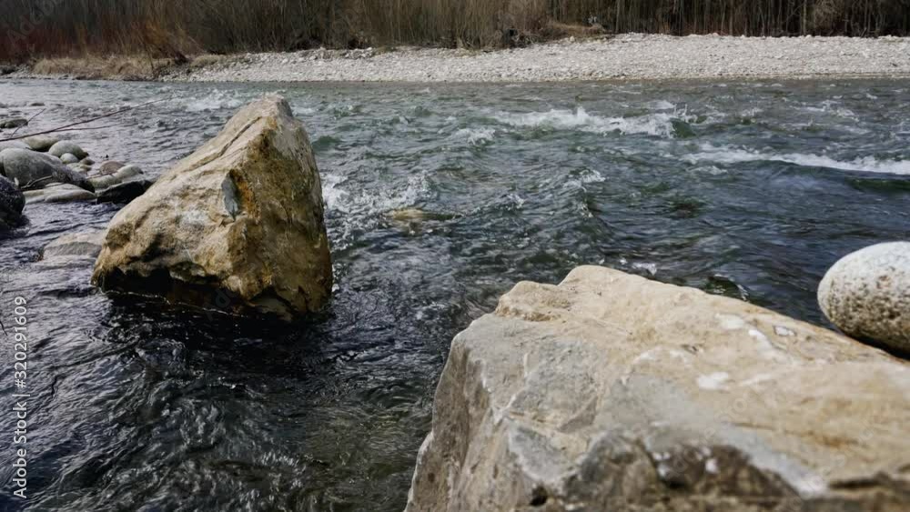 Water flowing in spring river, large rocks visible above surface Water flowing in spring river, large rocks visible above surface