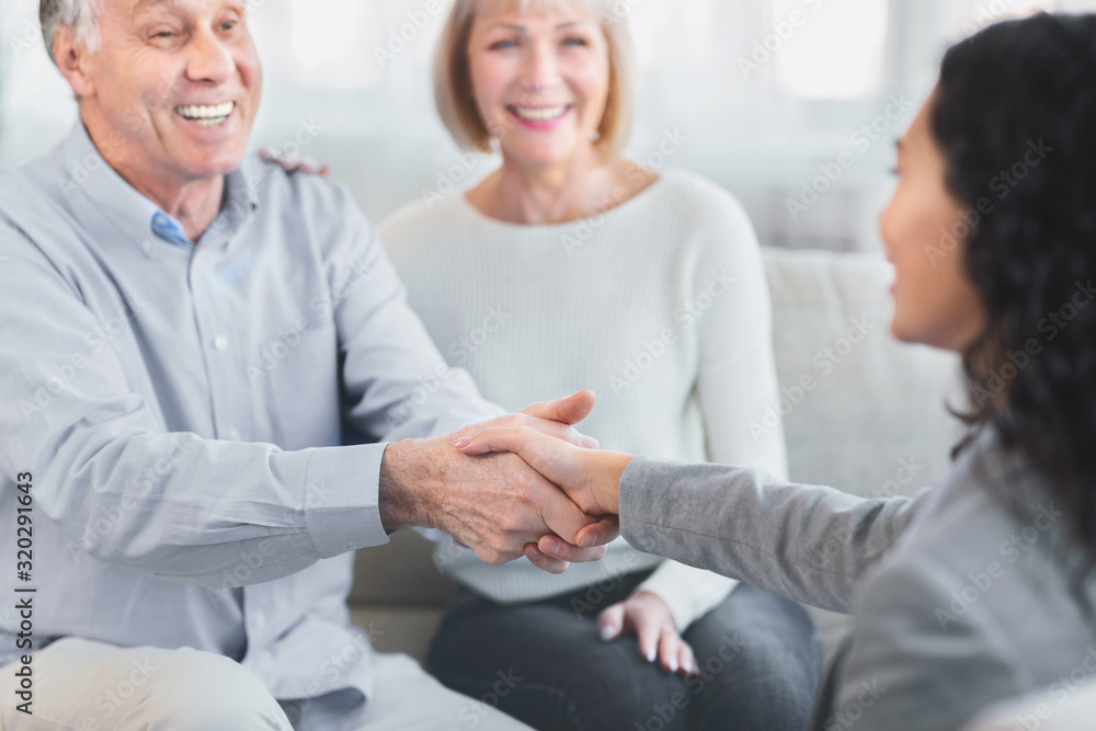 Fototapeta premium Happy senior couple giving female doctor handshake