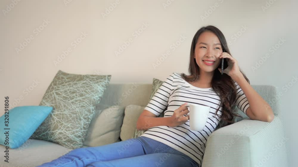 Smiling attractive woman on sofa laughing and speak to friends on a mobile phone