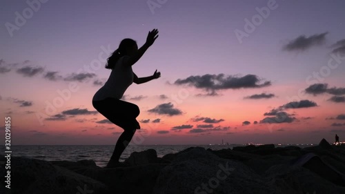 Wallpaper Mural Silhouette shot of a woman practicing Yoga standing position with her legs and arms crossed, shot during twilight near the ocean. Torontodigital.ca