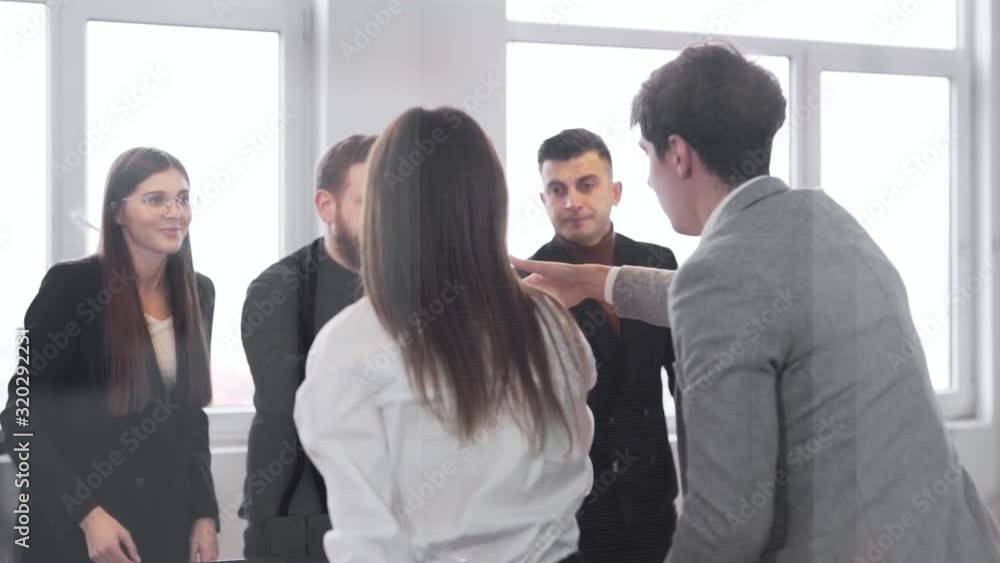 Business meeting of young people, shaking hands and handing papers, shooting businessmen through glass, closeup Business meeting of young people, shaking hands and handing papers, shooting businessmen through glass, closeup