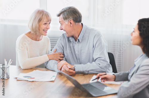 Mature couple talking to financial advisor at office