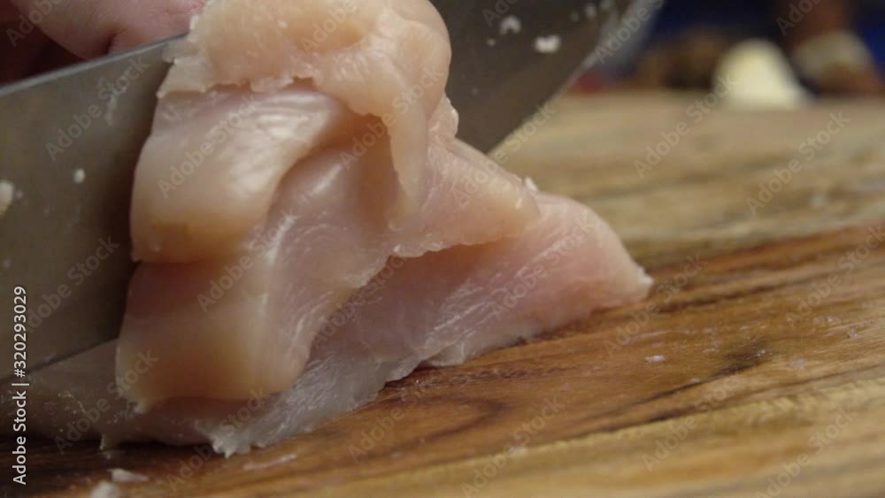 Chicken fillet on the cut board. Woman`s hands with a knife slices a delicate chicken fillet on the cut board. Chicken meat on the table. Slow motion Chicken fillet on the cut board. Woman`s hands with a knife slices a delicate chicken fillet on the cut board. Chicken meat on the table. Slow motion