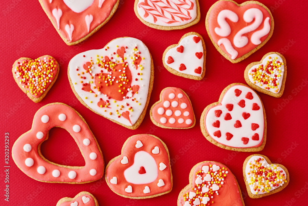 Background of decorated with icing and glazed heart shape cookies on the red background, flat lay. Valentines Day food concept Background of decorated with icing and glazed heart shape cookies on the red background, flat lay. Valentines Day food concept