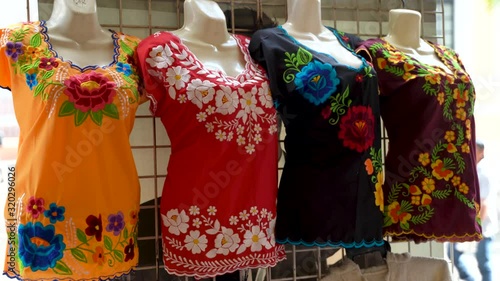 Camera turns to left as it moves right showing huipil Mexican blouses for women in a shop in Merida, Mexico. photo