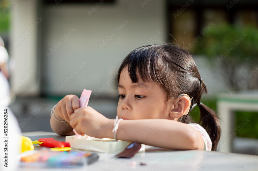 Hearing impaired children playing clay mold on the table in the park. Hearing impaired children playing clay mold on the table in the park.