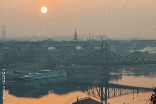 Photography Warm sunrise image of Budapest with a Liberty bridge view and reflections in Dan