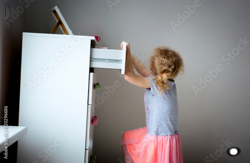 Fotografie Young girl child climbing on modern high dresser furniture, danger of dresser dipping over concept