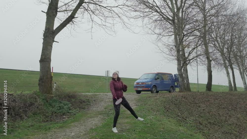 Slow motion of a lady playing badmington with a campervan in the background. A overcast and dull day, the shuttle cock coming from behind the camera towards the lady, the girl hitting back. Slow motion of a lady playing badmington with a campervan in the background. A overcast and dull day, the shuttle cock coming from behind the camera towards the lady, the girl hitting back.