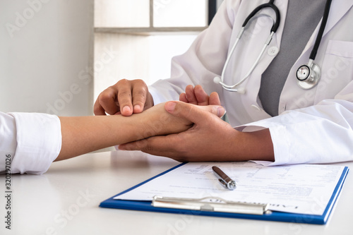The female doctor shaking hands the patient, examining the pulse on the upper arm with a finger, preliminary health examination at the hospital. Concepts of treatment and good health
