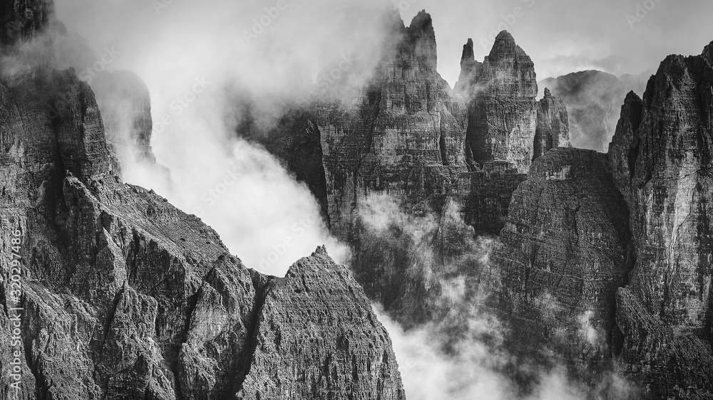 Black and white rocky mountains view covered with clouds, Dolomites, Italy