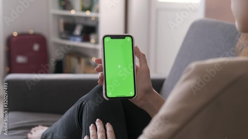 Wallpaper Mural Woman using mobile phone vertical green screen. Female holding in hand portable gadget close up indoors home living room. Mock-up for tracking or watching content. Blurred room on the background Torontodigital.ca