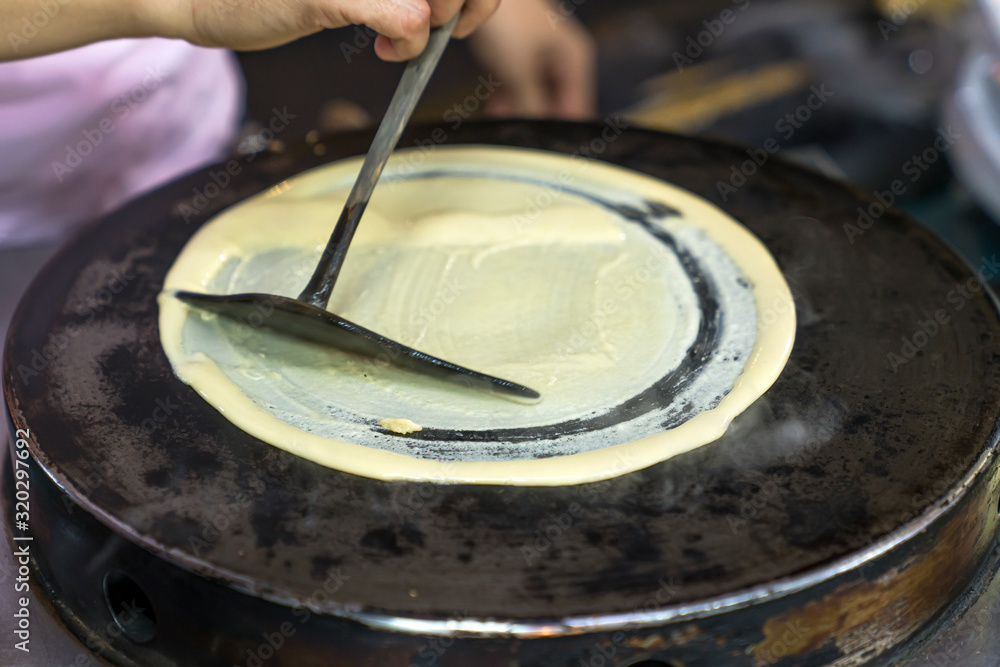 the process of frying pancakes, rolling out the dough on a hot pancake, forming a round pancake