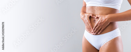 Prignant woman holding heart shaped hands against her small belly