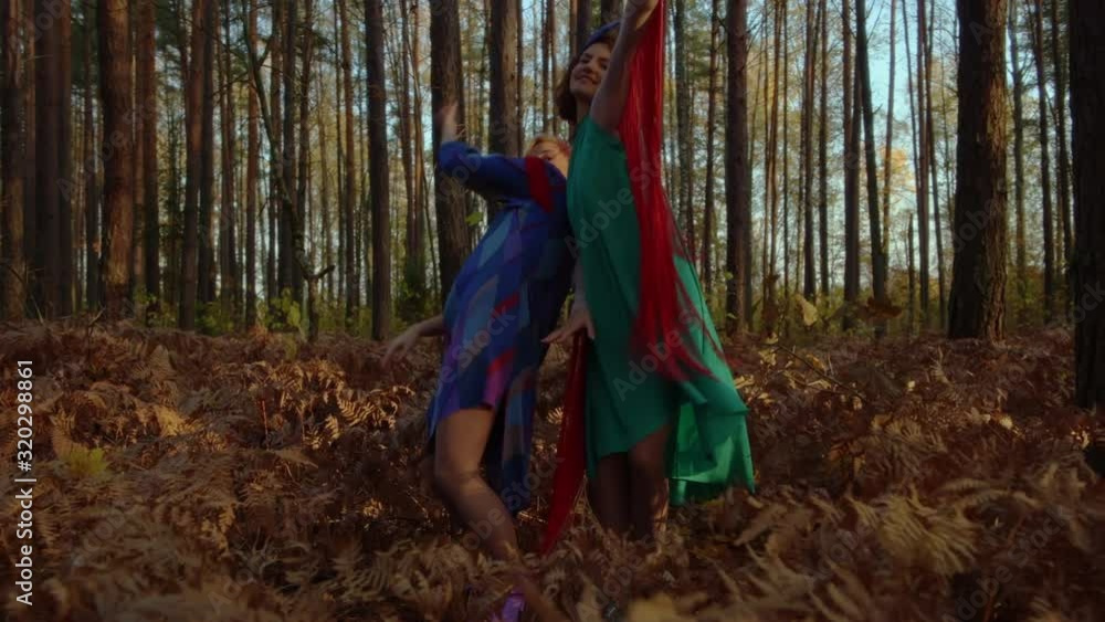 Moving shot of two women dancing sync in miraculous forest. Moving shot of two women dancing sync in miraculous forest.