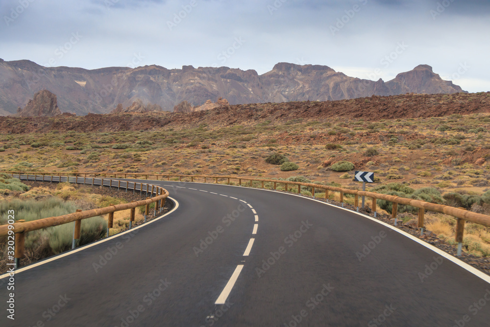 The road with blur in the foreground while driving and mountains with a volcano in the background