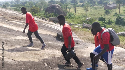 A slow motion shot of a group of athletic African beginning their ascent of a mountain in Africa. photo