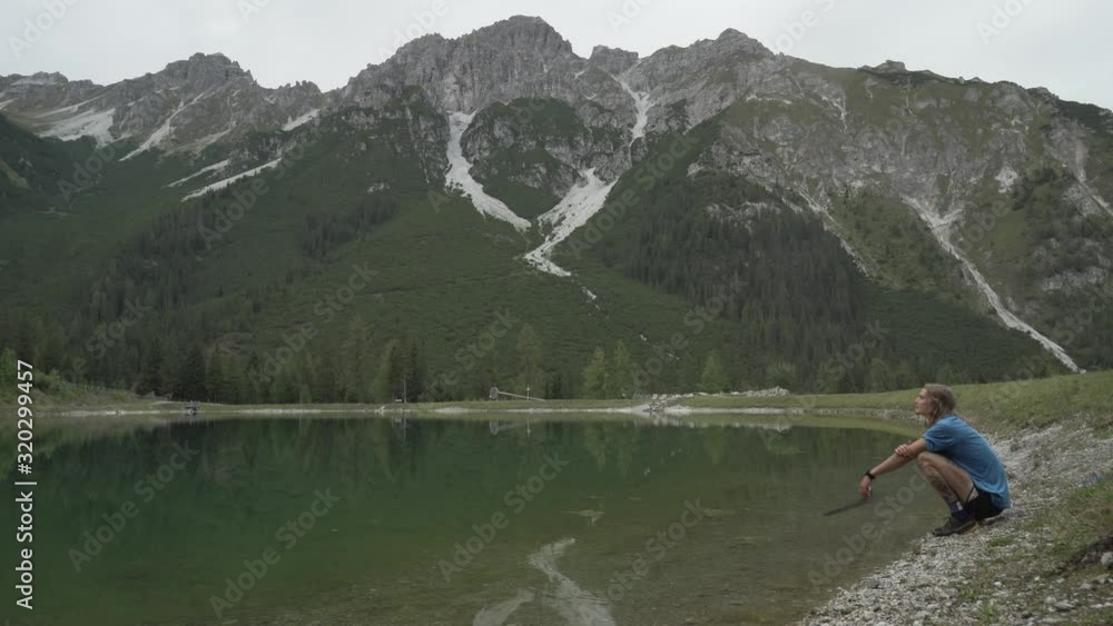 Mountain by a lake with runner resting by the lake, with cloudy weather, beautifull view in the alps in austria innsbruck 4k Mountain by a lake with runner resting by the lake, with cloudy weather, beautifull view in the alps in austria innsbruck 4k