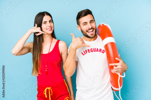 Young lifeguard couple isolated showing a mobile phone call gesture with fingers.