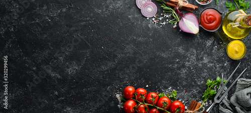 Obraz  z motywem Black stone cooking background. Spices and vegetables. Top view. Free space for your text.