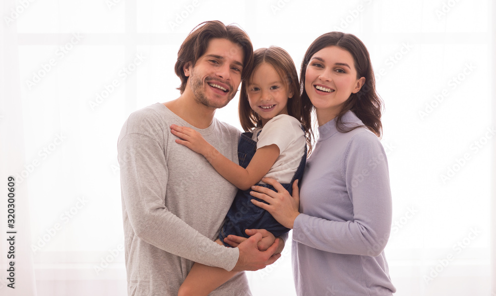 Smiling Parents Holding Little Daugher In Arms And Posing At Camera Smiling Parents Holding Little Daugher In Arms And Posing At Camera