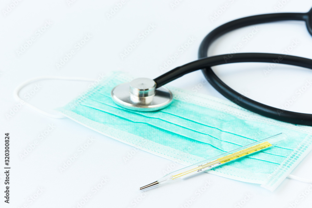 A thermometer, stethoscope and facial mask on white background A thermometer, stethoscope and facial mask on white background