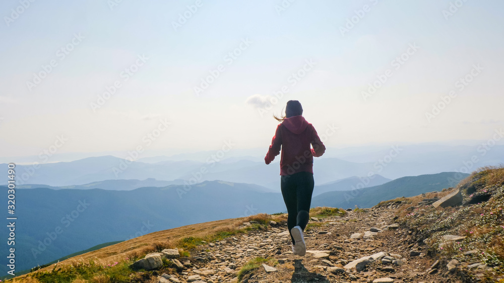 Obraz premium Back view of girl running on the mountain valley.
